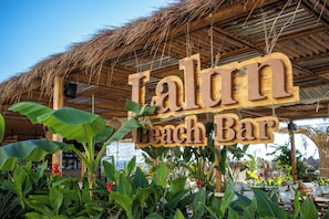A wooden sign for 'Talun Beach Bar' with a thatched roof and lush greenery. - LaLun Apartments & Rooms (Golem)