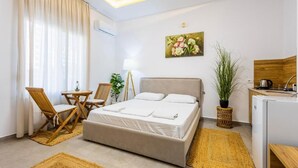 A bedroom with a bed, a desk, a chair, a lamp, and a painting on the wall.