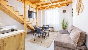 A wooden interior with a kitchen area, dining table, and sofa.