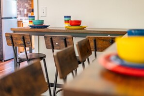 A dining area with wooden chairs, a table, and colorful bowls and plates.
