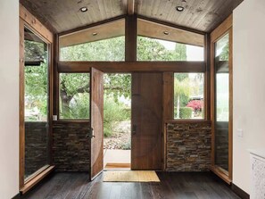 Ein geräumiger Eingangsbereich mit Holzboden, großen Glasüren und einer Steinwand.