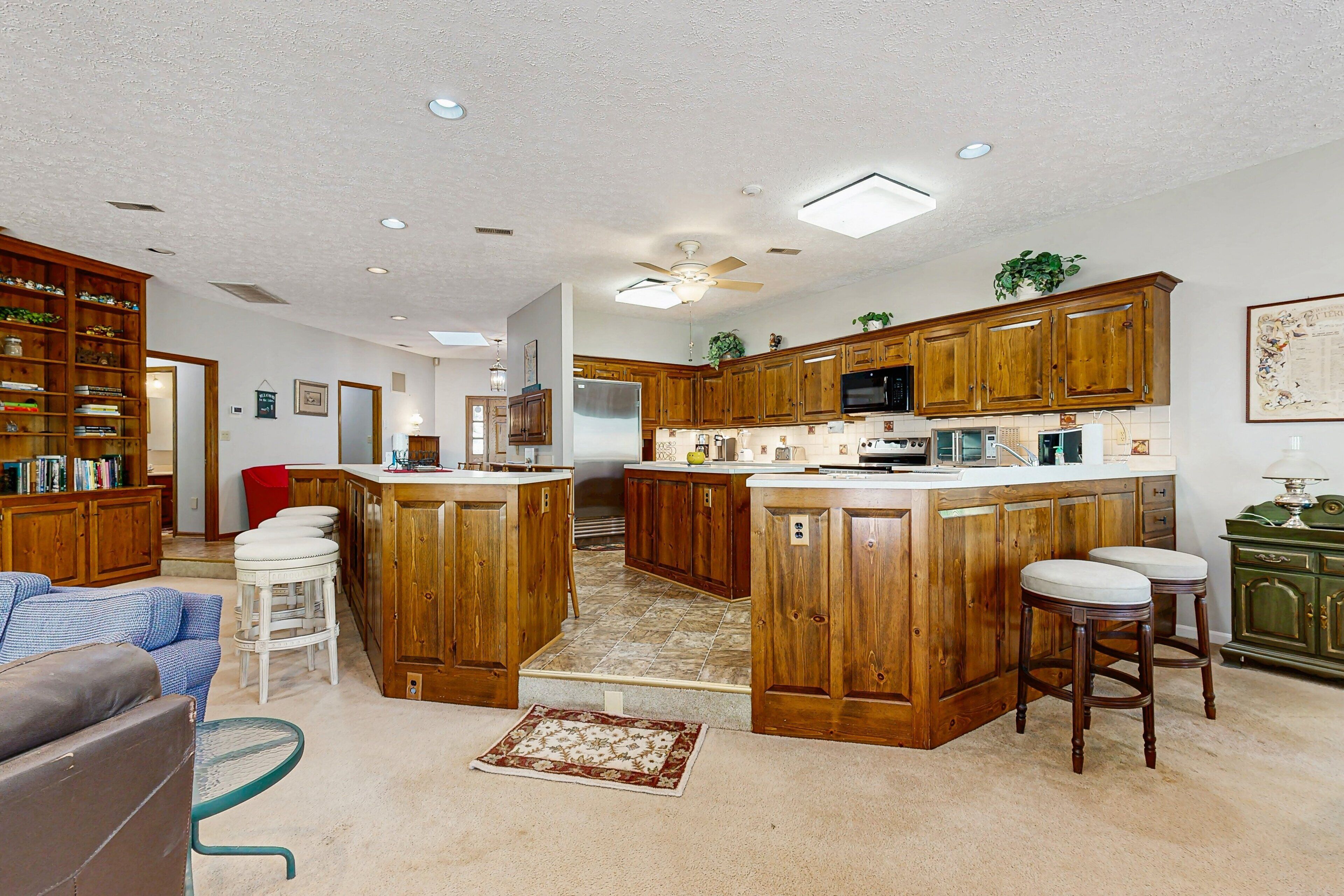 A spacious kitchen with wooden cabinets, a central island, and bar stools.