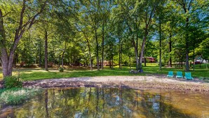 Un parco tranquillo con uno stagno, un prato verde e una fila di sedie blu.