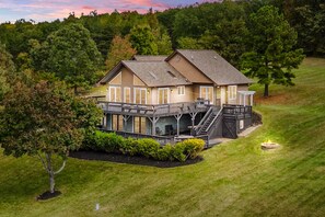 A two-story house with a deck and a fire pit. - Updated Lakefront Home & Studio With Water Views, hot Tub, Dock & Game Room (Spotsylvania)