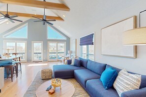 A spacious living area with a large sectional sofa, a round coffee table, and a dining area with a table and chairs. - Updated Lakefront Home & Studio With Water Views, hot Tub, Dock & Game Room (Spotsylvania)