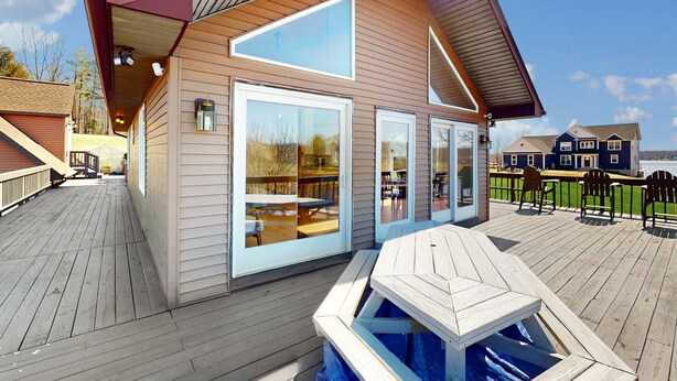 A wooden deck with a pool, a covered patio, and a view of a lake. - Updated Lakefront Home & Studio With Water Views, hot Tub, Dock & Game Room (Spotsylvania)