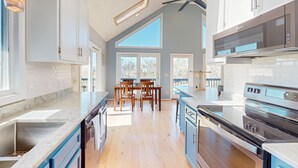 A modern kitchen with a large island, built-in appliances, and a dining area with natural light. - Updated Lakefront Home & Studio With Water Views, hot Tub, Dock & Game Room (Spotsylvania)