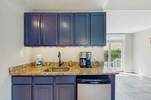 A kitchen with dark cabinets, a granite countertop, a dishwasher, and a coffee maker. - Updated Lakefront Home & Studio With Water Views, hot Tub, Dock & Game Room (Spotsylvania)