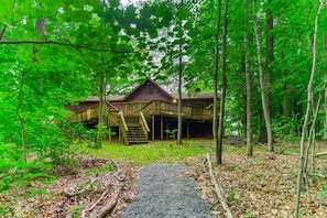 Eine Holzhütte mit überdachter Terrasse, umgeben von dichtem Wald.