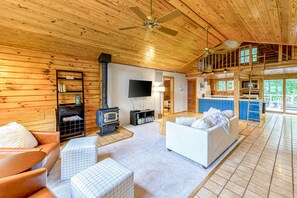 Ein Blockhaus-Interieur mit Kamin, Sofa, Fernseher und einem Schlafloft.