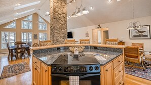 A kitchen with a large island, stone pillar, and multiple windows. - Stunning Lakeside Home With Dock, Large Deck, Firepit, Kayaks & Pool Table (Bumpass)