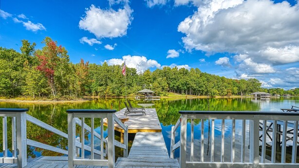 A wooden dock leading to a calm lake with a gazebo in the distance, surrounded by trees and a clear sky. - Stunning Lakeside Home With Dock, Large Deck, Firepit, Kayaks & Pool Table (Bumpass)