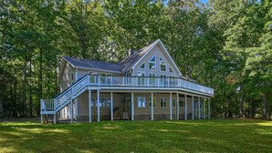 A large, two-story house with a wrap-around porch, a staircase leading to the upper level, and a stone foundation. - Stunning Lakeside Home With Dock, Large Deck, Firepit, Kayaks & Pool Table (Bumpass)