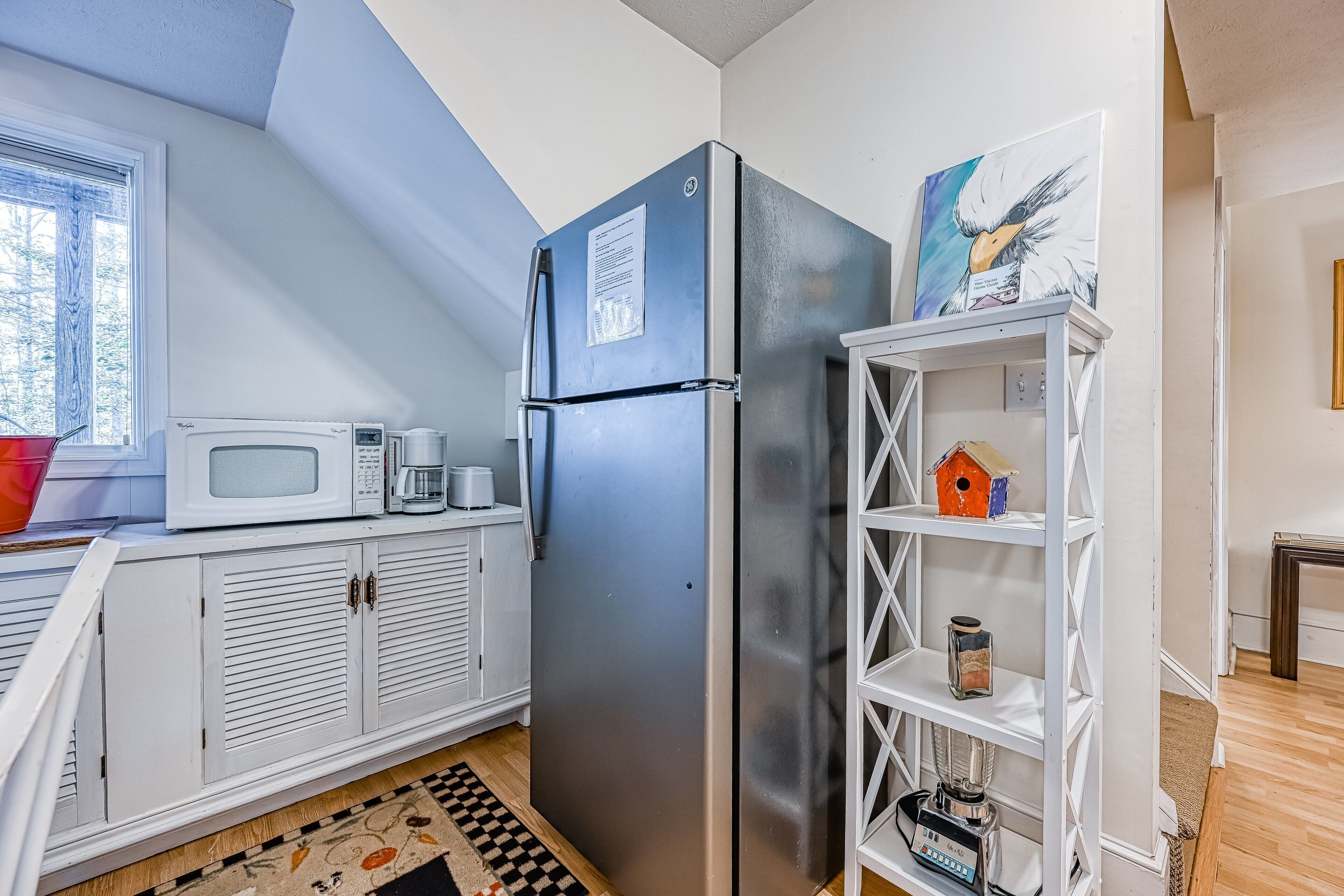 A compact kitchen with a refrigerator, microwave, and coffee maker on a white cabinet.