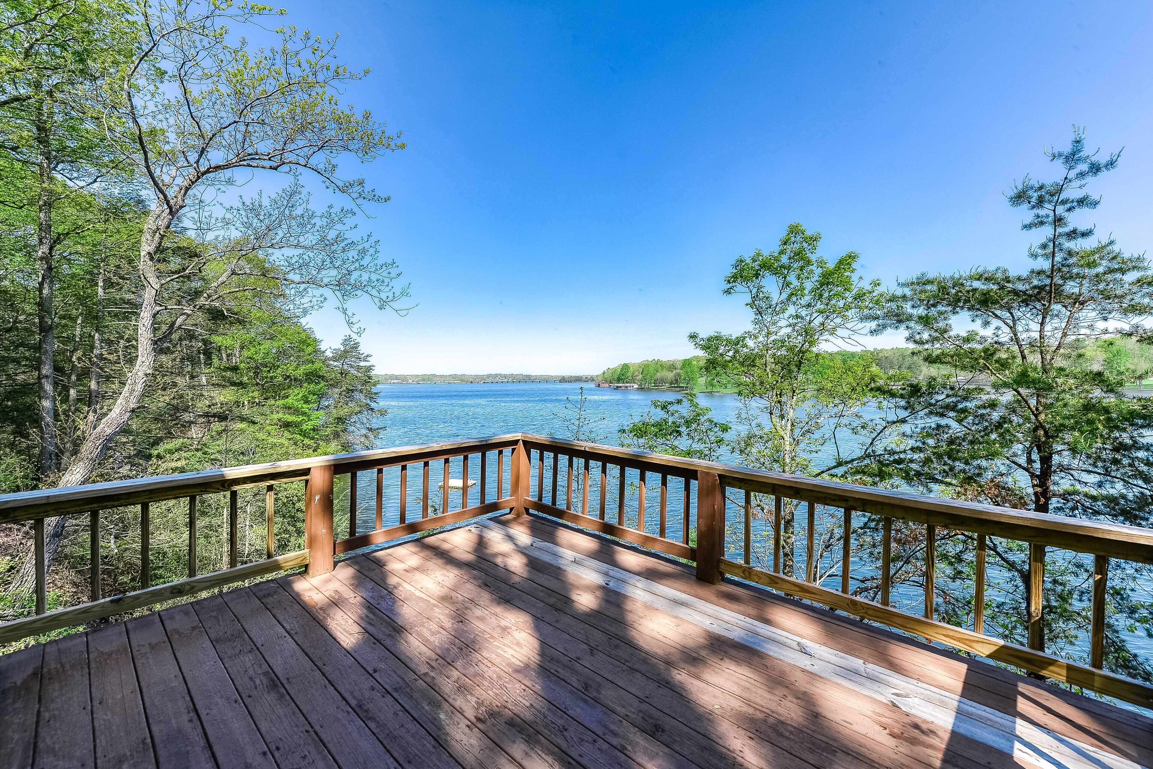 A wooden deck with a railing overlooking a body of water and trees.
