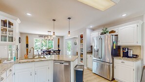 A modern kitchen with white cabinetry, stainless steel appliances, and a granite countertop. - Lakefront House With Breathtaking Views, Private Dock & Boat Launch (Mineral)