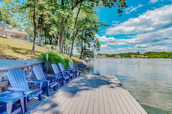 A wooden dock with blue Adirondack chairs, a stone wall, and a house in the background. - Lakefront House With Breathtaking Views, Private Dock & Boat Launch (Mineral)