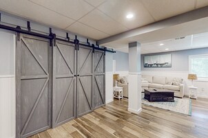 Una habitación con un gran door de granero corredizo, un sofá, una mesa de centro y un cuadro en la pared.