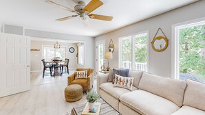 A spacious living room with a ceiling fan, large windows, a sofa, a coffee table, and a dining area. - Lakefront House With Breathtaking Views, Private Dock & Boat Launch (Mineral)