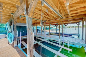 Terraza de madera con piscina, vigas de madera y zona de estar cubierta.