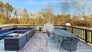 A deck with outdoor furniture, including a table and chairs, and a covered grill area. - Peaceful Lakeside Retreat With hot Tub, Private Pool, Dock & Paddle Boards (Orange)