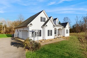 A two-story white house with a garage, a covered porch, and a well-maintained lawn. - Peaceful Lakeside Retreat With hot Tub, Private Pool, Dock & Paddle Boards (Orange)