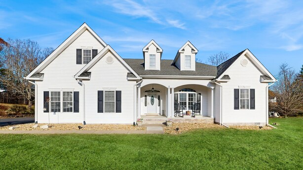 A two-story white house with a central entrance, a covered porch, and a well-maintained lawn. - Peaceful Lakeside Retreat With hot Tub, Private Pool, Dock & Paddle Boards (Orange)