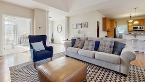 A spacious living area with a sofa, armchair, ottoman, and patterned rug. - Peaceful Lakeside Retreat With hot Tub, Private Pool, Dock & Paddle Boards (Orange)