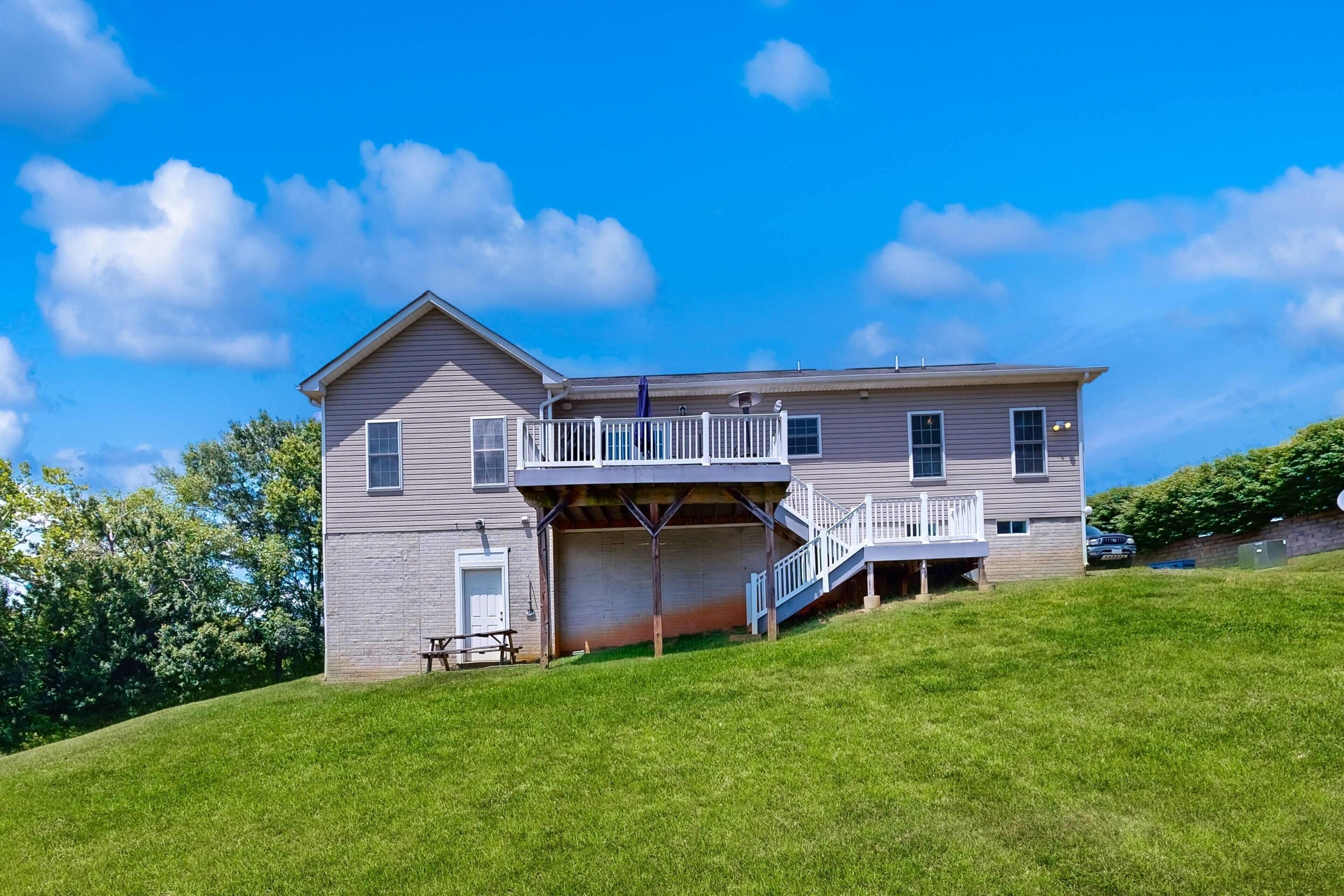 A two-story house with a covered porch and a small deck.