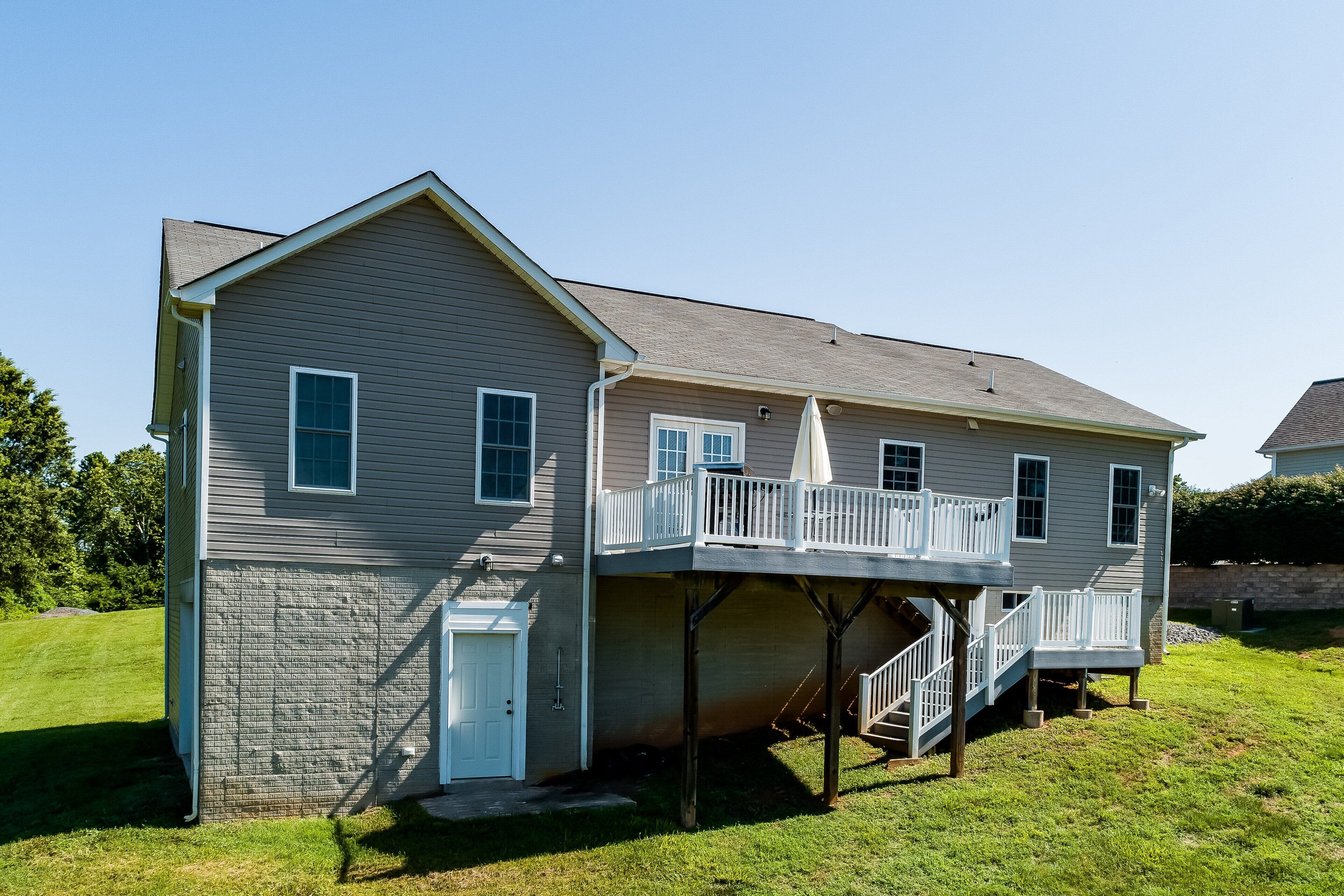 A two-story house with a covered deck and a front door.