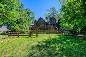 A large wooden house with a balcony, surrounded by lush green trees. - Luxurious Lakefront Cabin With hot Tub, Game Room, & Washer/dryer- dog Friendly (Bumpass)