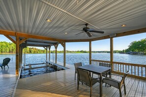 Um deck coberto com mesa e cadeiras, uma piscina e vista para a água.