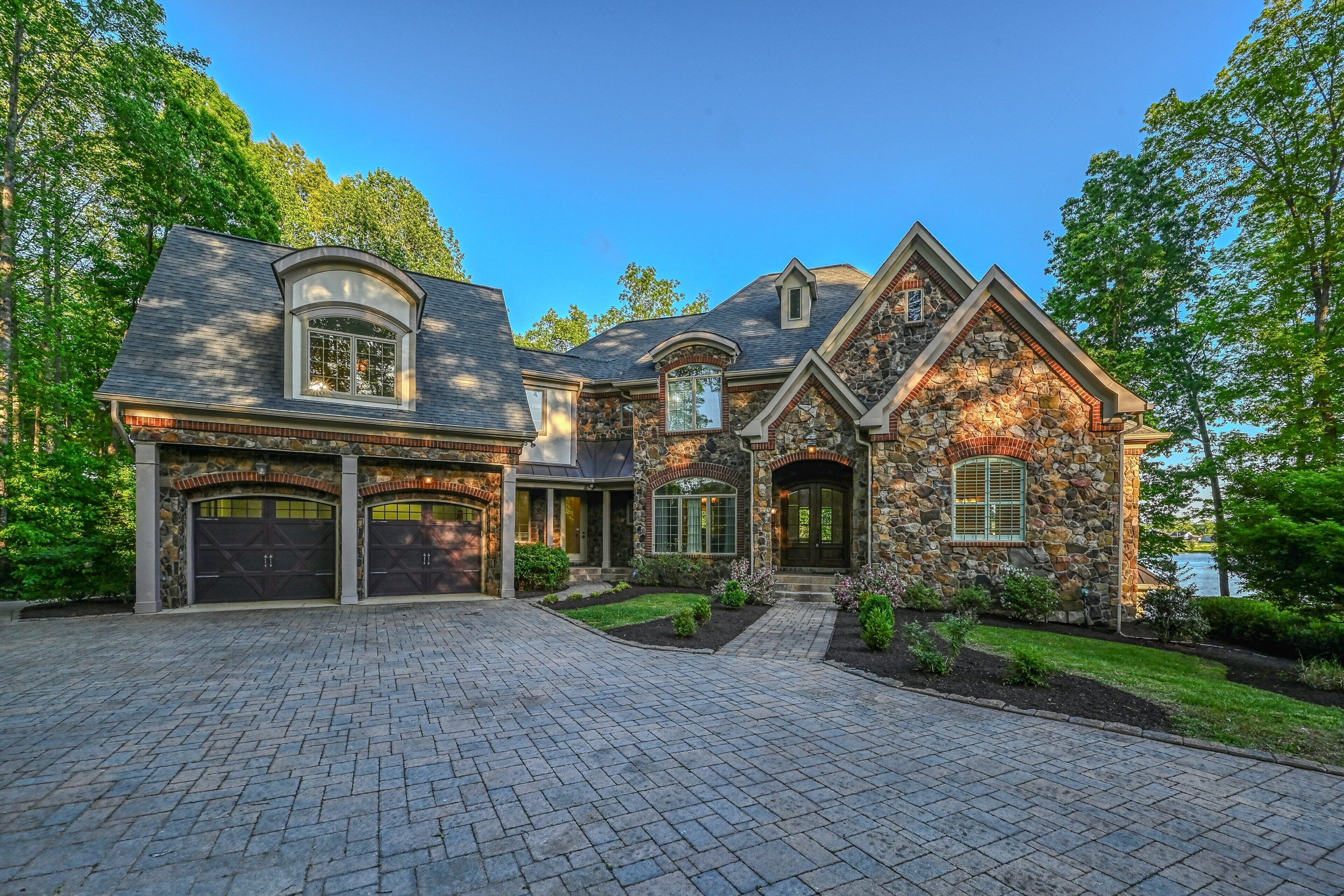 A large, two-story house with a stone facade, multiple garage doors, and a well-maintained driveway.