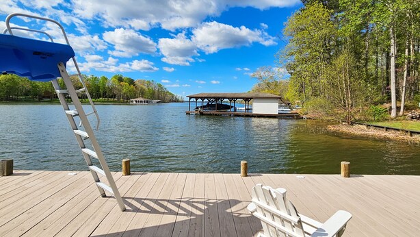 A wooden dock with a ladder, a covered seating area, and a boat on the water. - Tranquil Lakefront Retreat With hot Tub, Screened Porch, Kayaks, and More (Bumpass)