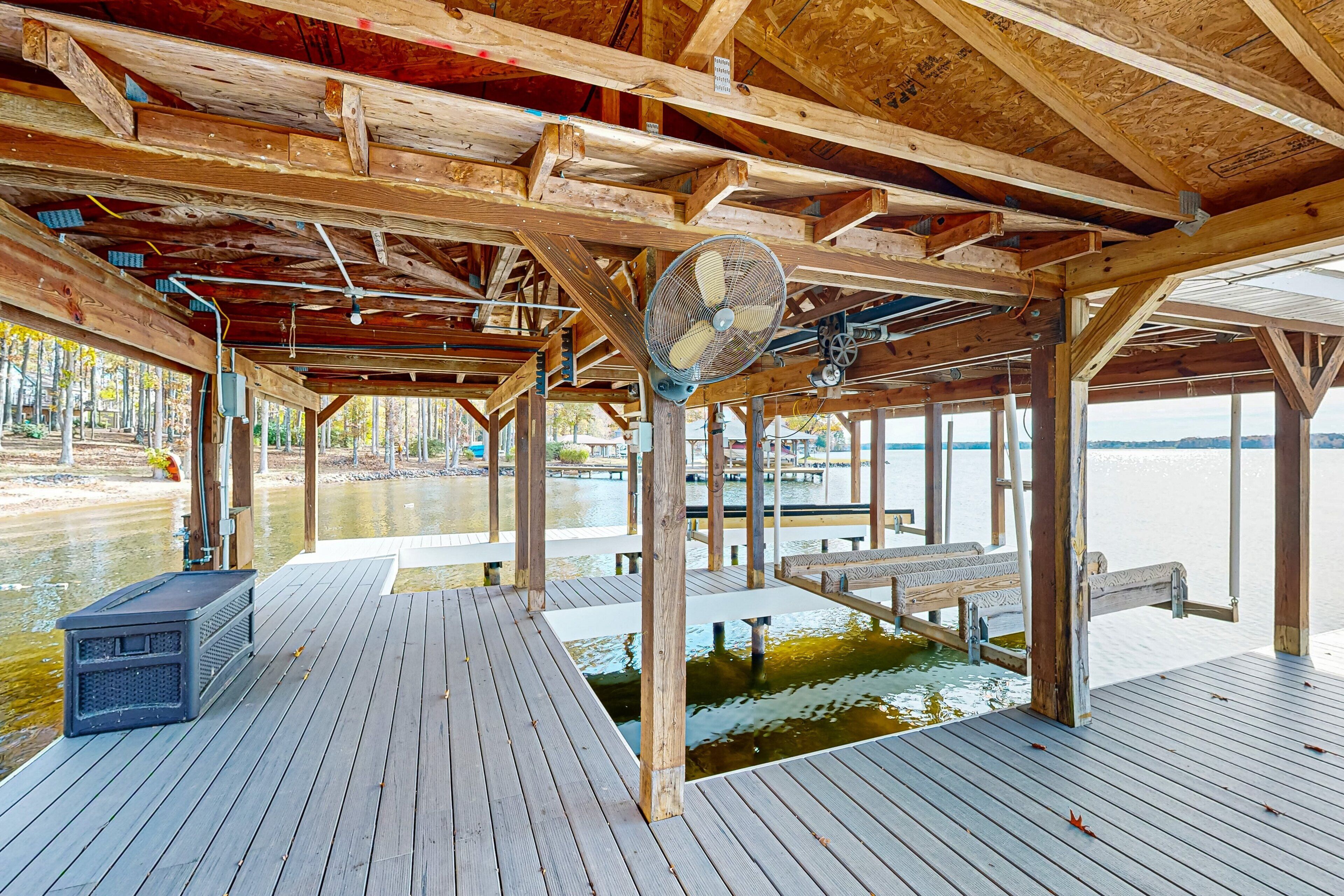 Une terrasse en bois avec un ventilateur, des bancs et une vue sur une étendue d’eau.