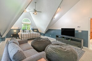 A loft bedroom with a bed, a TV, and a seating area. - Stunning Lakefront House With View, Free Wifi and Secluded Swimming Area (Spotsylvania)