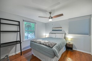 A bedroom with a bed, a ceiling fan, a window, a nightstand, and a shelf. - Quiet Lake Home With two Kayaks, Furnished Deck, Grill & Fast Wifi - Dogs OK (Mineral)