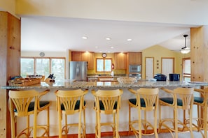 A kitchen with wooden cabinets, a granite countertop, and bar stools. - Lakefront Retreat With Views, hot Tub, Kid's Play Area, Dock & Fiber Internet (Mineral)