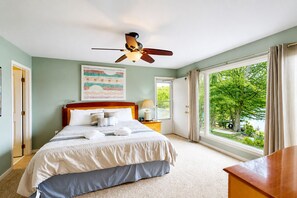 A bedroom with a bed, a ceiling fan, a window with curtains, and a painting on the wall. - Lakefront Retreat With Views, hot Tub, Kid's Play Area, Dock & Fiber Internet (Mineral)