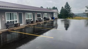 A motel with a covered parking area, outdoor seating, and a view of the surrounding landscape. - Ja-Sa-Le Motel (Bubartown)