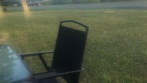 A grassy outdoor area with a metal chair and a table, likely part of a hotel or resort. - Ja-Sa-Le Motel (Bubartown)
