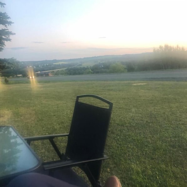 A grassy outdoor area with a metal chair and a table, likely part of a hotel or resort.