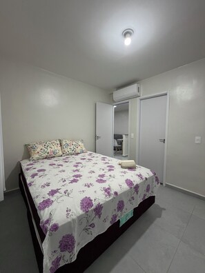 A bedroom with a bed, a wardrobe, an air conditioning unit, and a door.