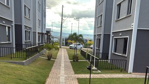 A paved pathway leading to a modern building complex with multiple floors and balconies.