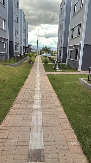 A paved pathway leading to a modern building complex with multiple floors and balconies.