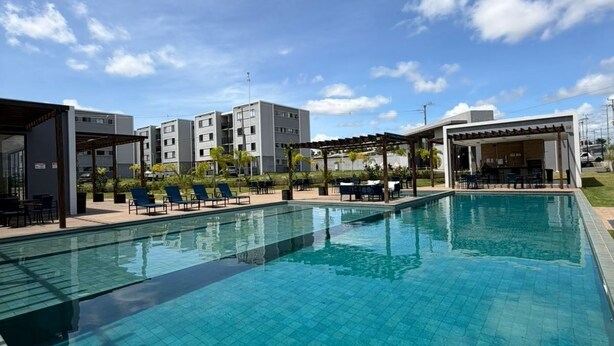 A swimming pool with tiled flooring, adjacent buildings, and outdoor seating areas.