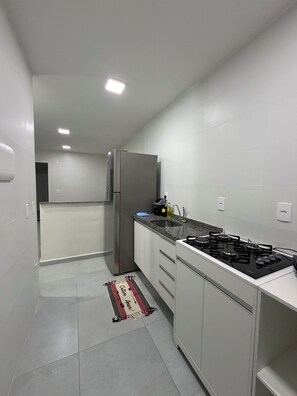 A modern kitchen with a stainless steel refrigerator, a gas stove, and a granite countertop.