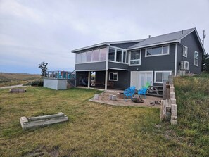 A modern two-story house with a covered patio, outdoor seating, and a view of the surrounding landscape. - Relaxing 5-bedroom house with one of the best views at Lake Mac. (Brule)