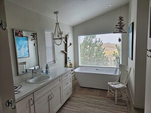 A modern bathroom with a bathtub, a large window, and a mirror. - Relaxing 5-bedroom house with one of the best views at Lake Mac. (Brule)