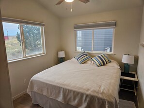 A bedroom with a bed, two windows, a ceiling fan, and bedside lamps. - Relaxing 5-bedroom house with one of the best views at Lake Mac. (Brule)